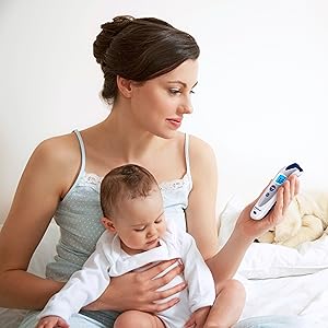 Mother with child in her arms looks at fever thermometer