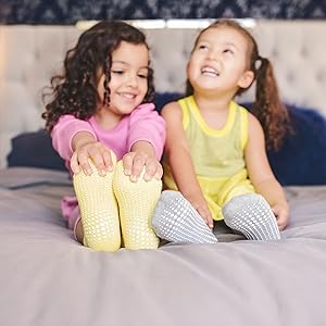 dos chicas en la cama en amarillo gris agarre calcetines riendo sonriendo cómodo mostrando dedo